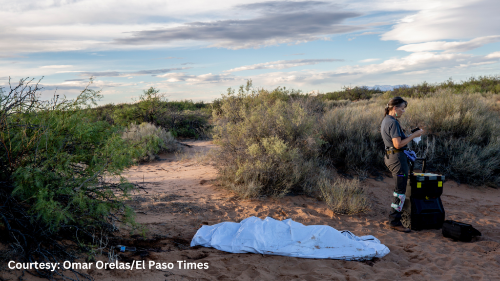 A man standing next to a blanket in the desert.