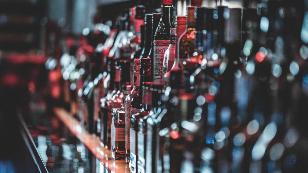 Many bottles of wine are lined up on a bar.