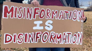 A group of people holding up a sign that says misinformation is disinformation, discussing the significance of water in combating fake news.