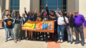 A group of people standing in front of a building with a banner advocating for water rights.