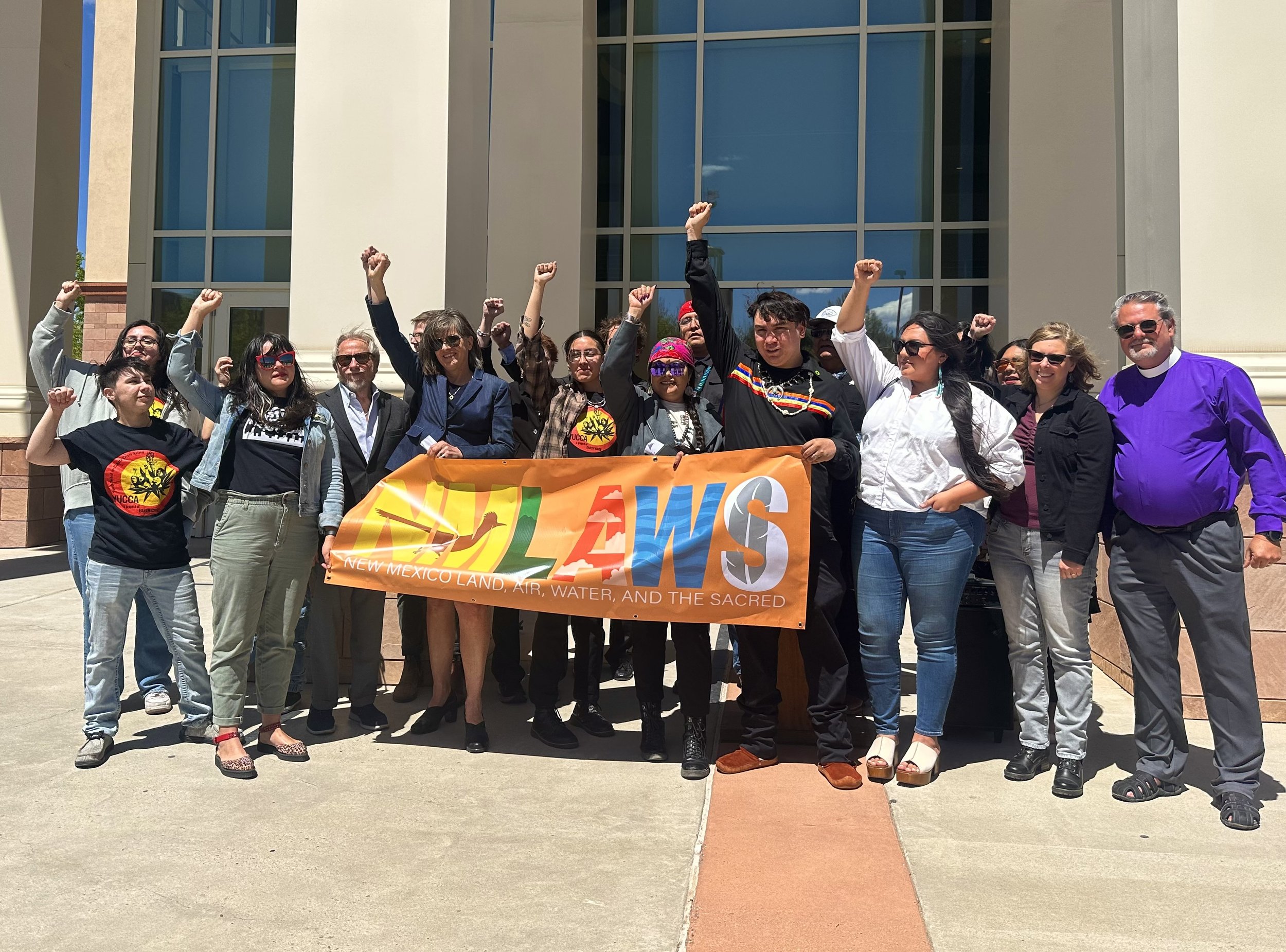 A group of people standing in front of a water building with a banner.