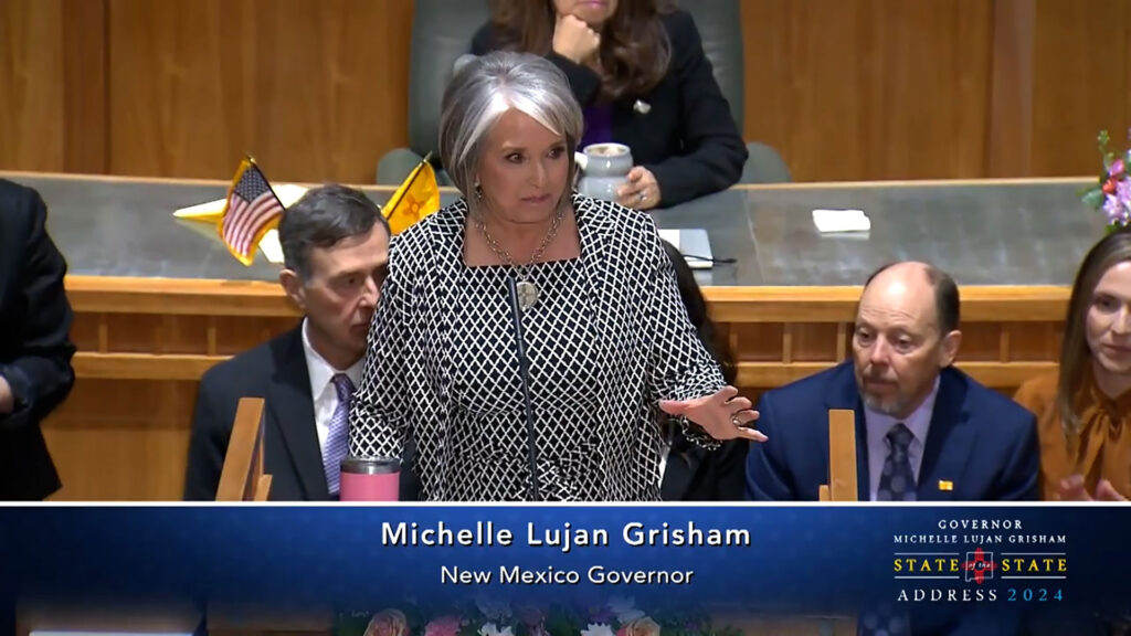 A woman in a suit and tie is giving a speech.