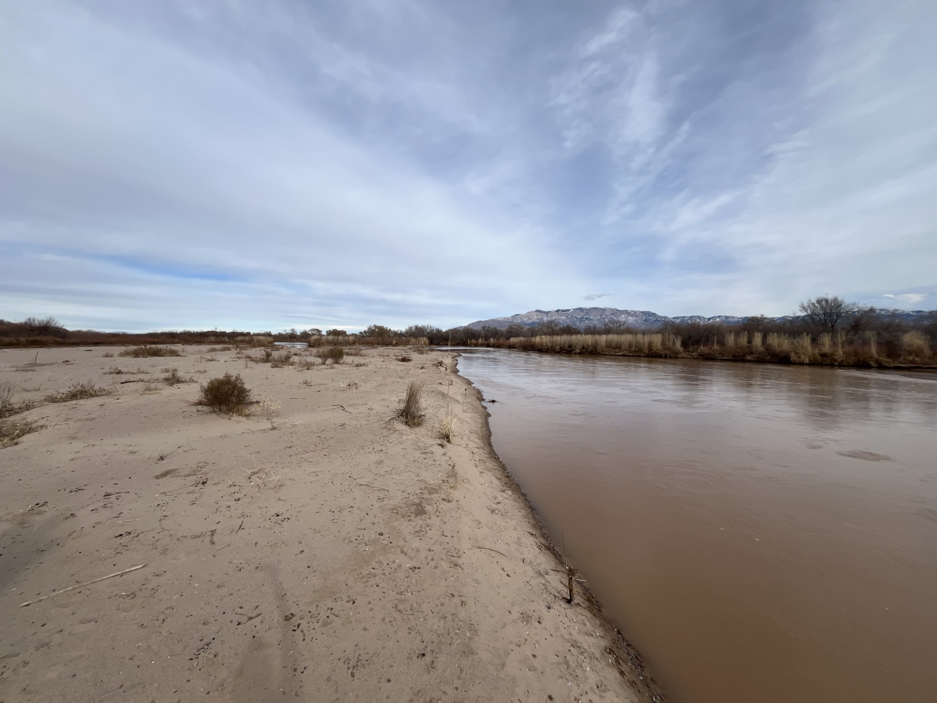 A view of a river in the desert with mountains in the background, featuring water.