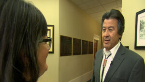 A man in a suit talking to a woman in a hallway.