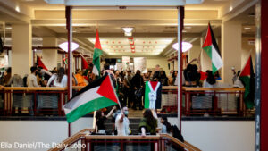 People holding palestinian flags during a rally inside a building with balconies.