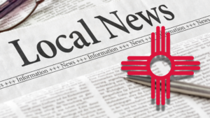 Newspaper with the headline "Local News" and the Zia sun symbol, representing New Mexico, on top of the publication. Glasses are partially visible in the top left corner.