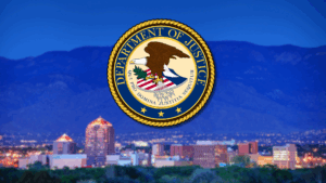 The U.S. Department of Justice seal overlaid on a blurred cityscape with mountains in the background during dusk.