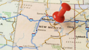 A red pushpin marks a location on a map of New Mexico, highlighting nearby cities such as Albuquerque, Santa Fe, and Roswell.