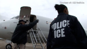 Two ICE officers stand near an airplane with an open door and boarding stairs, preparing for boarding. "Courtesy of: ICE YouTube" is visible in the upper right corner.