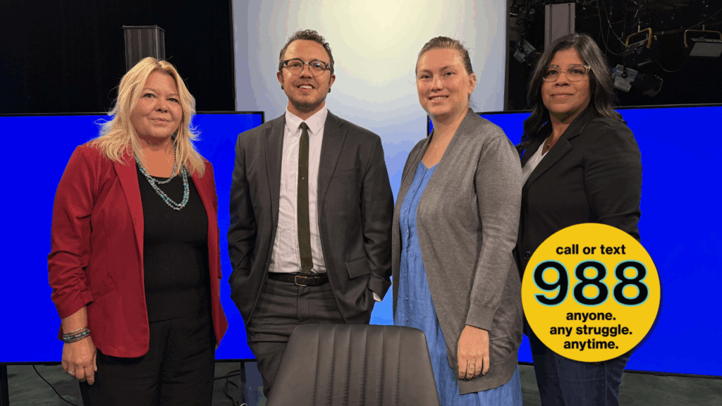 Four people stand together in a studio with blue screens behind them; a yellow badge reads, "call or text 988 anyone. any struggle. anytime.