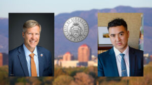 Two men in suits are positioned on either side of the City of Albuquerque seal, with a blurred cityscape and mountains in the background.