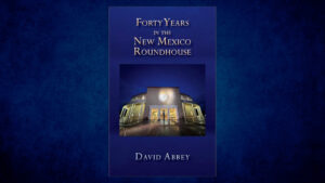 Book cover for "Forty Years in the New Mexico Roundhouse" by David Abbey, featuring a nighttime photo of the New Mexico State Capitol building.
