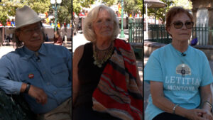 Three adults sit separately outdoors on benches, divided by black lines. Two wear glasses; one wears a hat. Tents and trees are visible in the background.