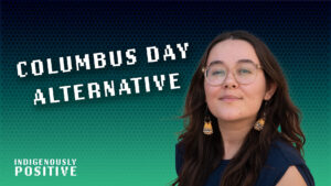 A person with long hair and glasses stands in front of a gradient background with the text "Columbus Day Alternative" and "Indigenously Positive.