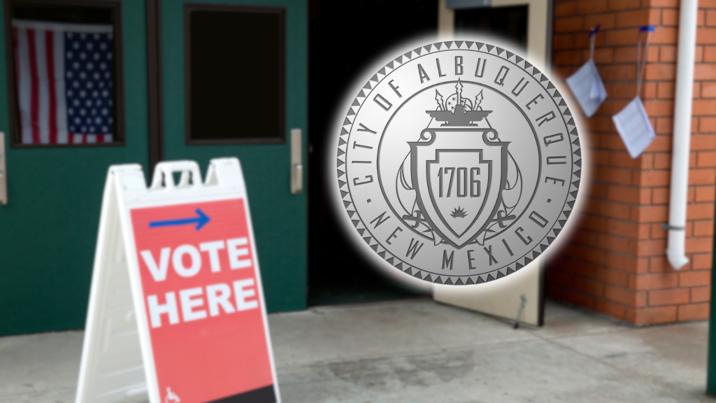 A "Vote Here" sign stands outside an entrance with the City of Albuquerque, New Mexico seal overlaid on the image; an American flag hangs in the background.