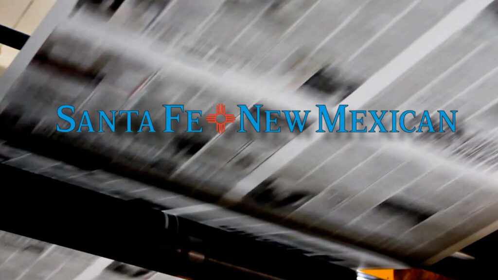 The words "Santa Fe New Mexican" appear over a blurred image of newspapers moving through a printing press.