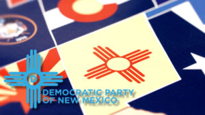 A close-up of various state flags, with the New Mexico flag prominent. “Democratic Party of New Mexico” logo and text are overlaid in the lower left corner.