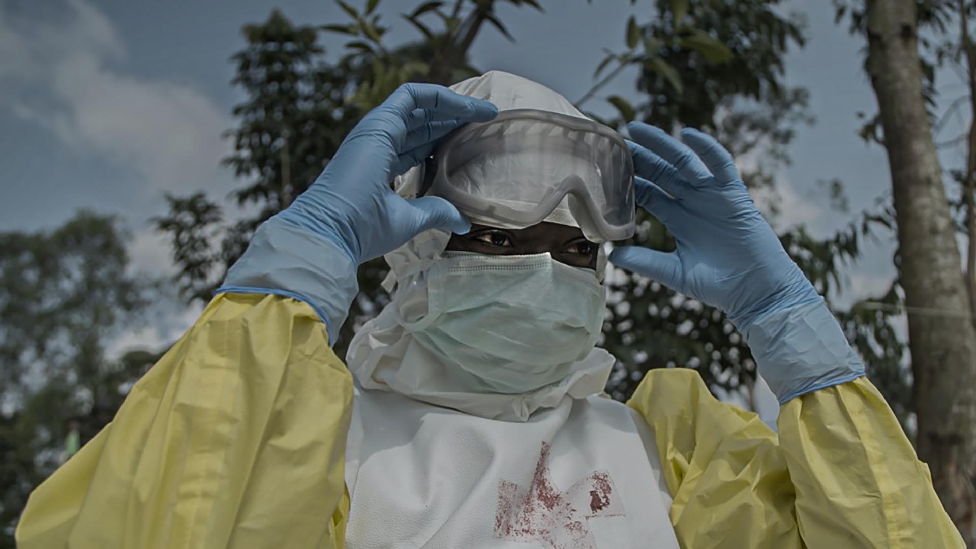 Ebola in Congo A medical worker peels off their goggles and looks off-screen.