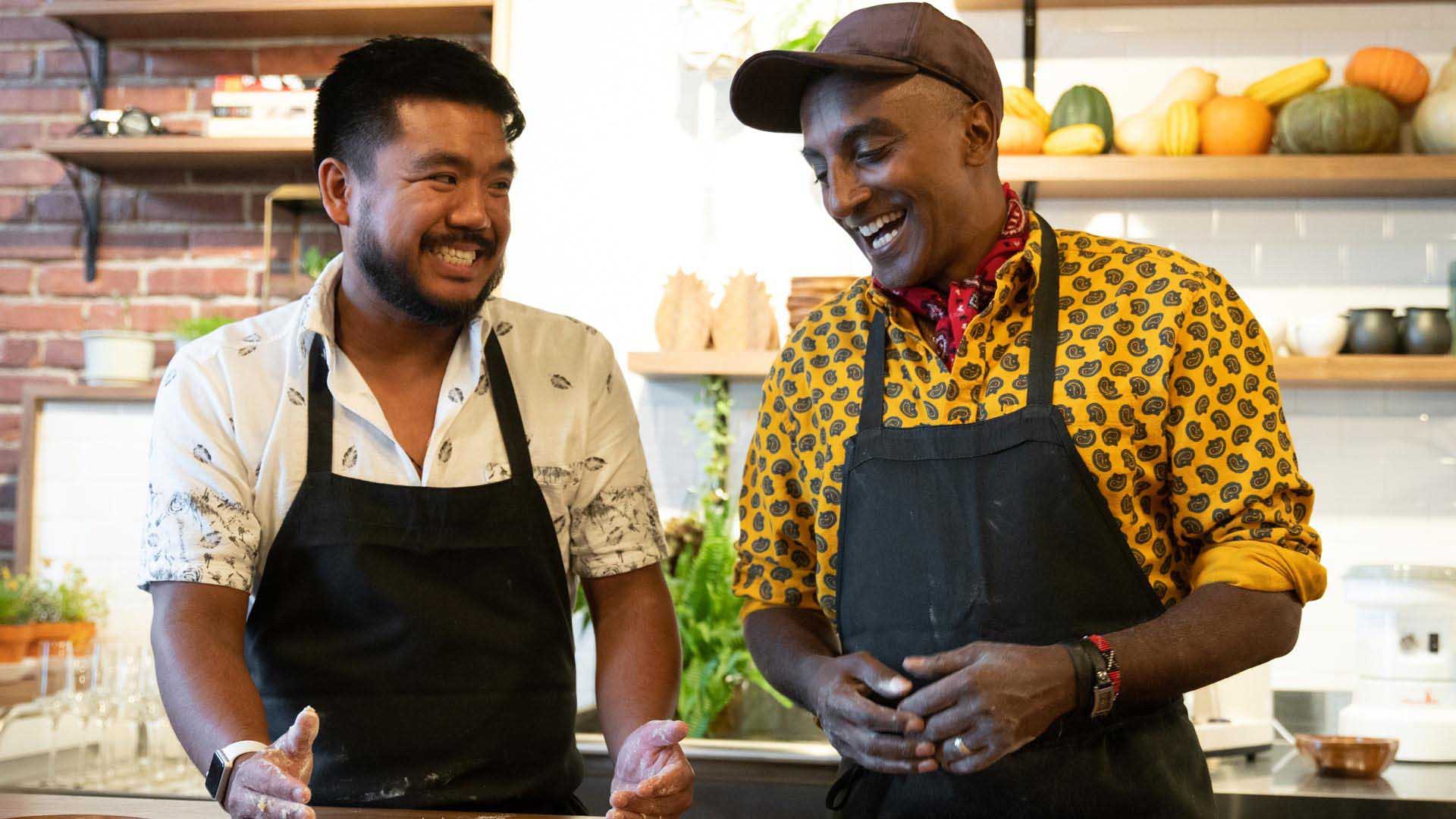 No Passport Required Seattle Two people laugh and cook with each other in a kitchen.