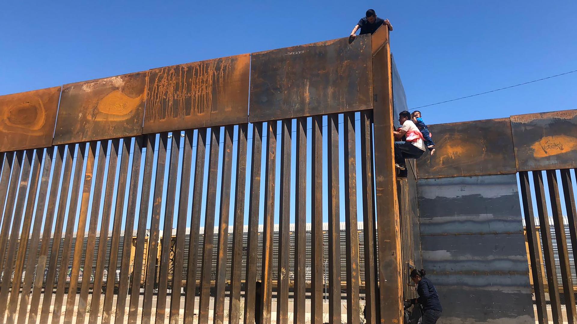 People climb over a border wall in the southern United States.