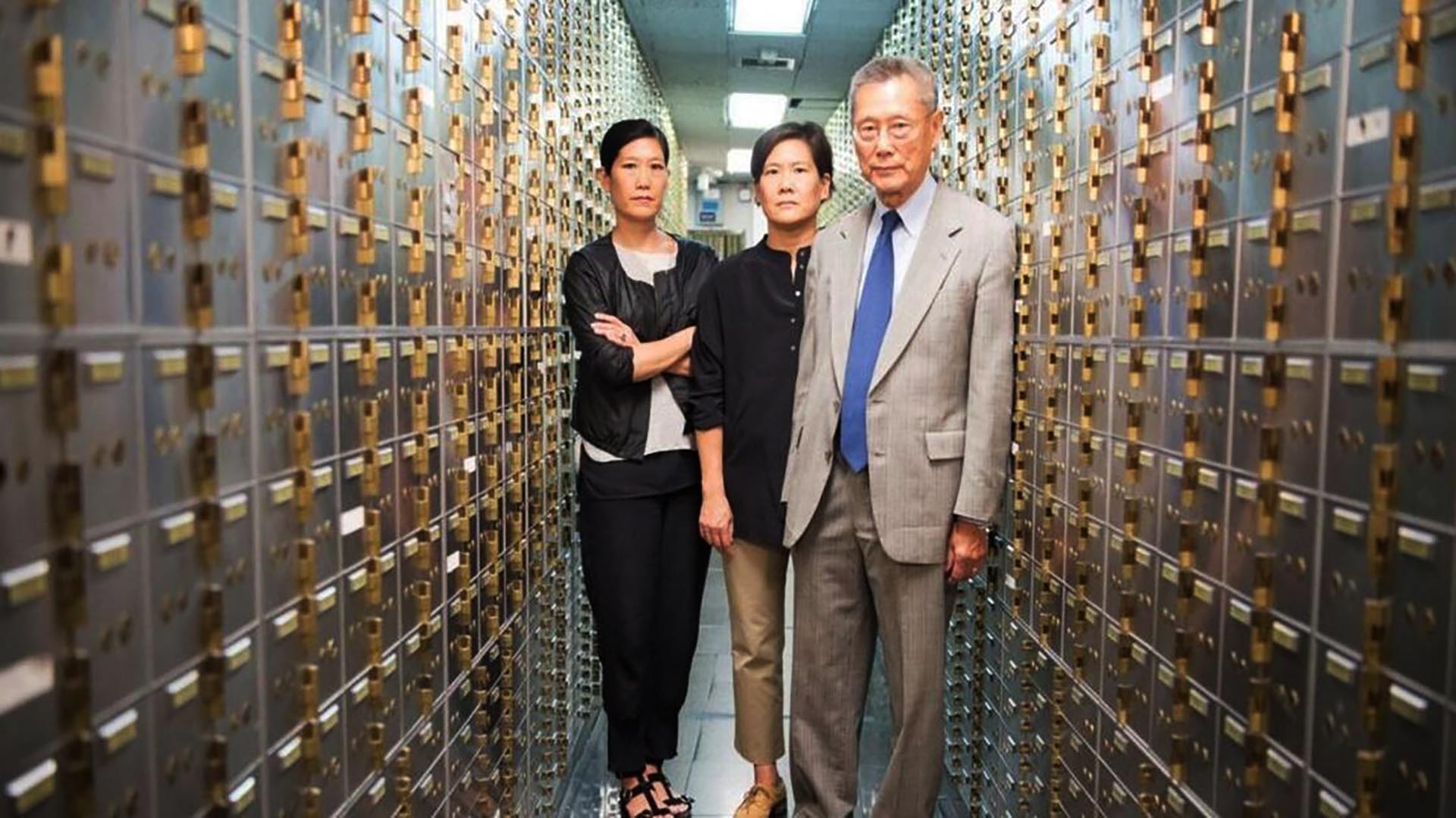 Three people stand and pose in the midst of a computer room.